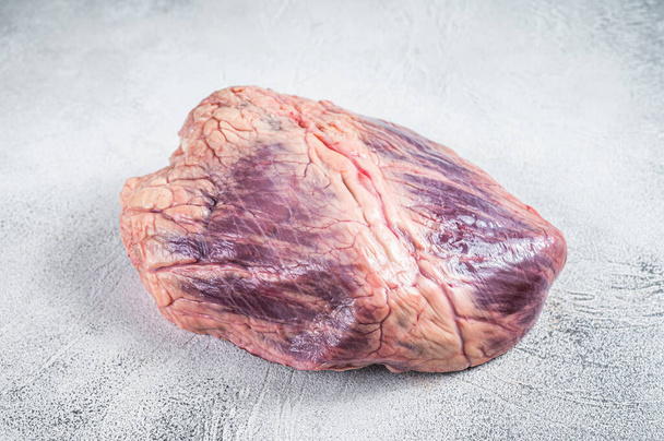Carne de res o ternera corazón crudo en una mesa de carnicero. Fondo blanco. Vista superior - Foto, imagen