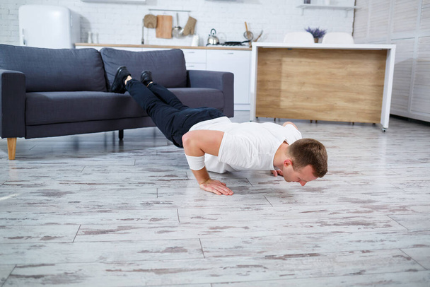 A young man goes in for sports at home, he does push-ups on the couch. Healthy lifestyle - Zdjęcie, obraz