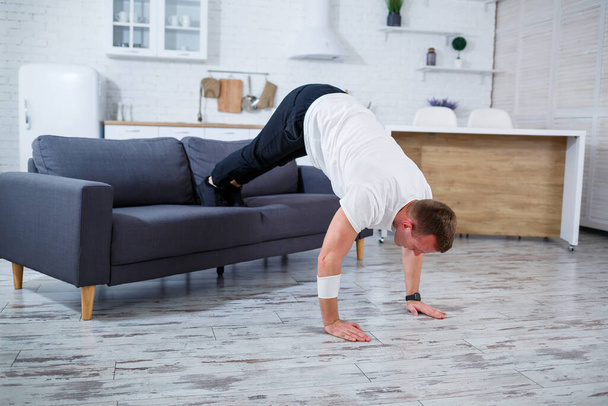 Egy fiatalember bemegy sportolni otthon, fekvőtámaszozik a kanapén. Egészséges életmód - Fotó, kép