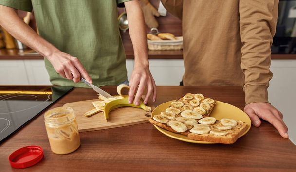 Young gay couple cutting banana standing side by side - Photo, Image