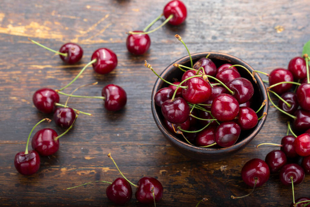 Freshly harvested cherries in a clay bowl from your home garden. Healthy food concept - 写真・画像