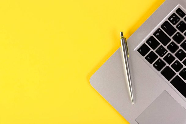 Leptop, notebook, pen, on a yellow background. Flat lay. Copy space. - Foto, Imagen