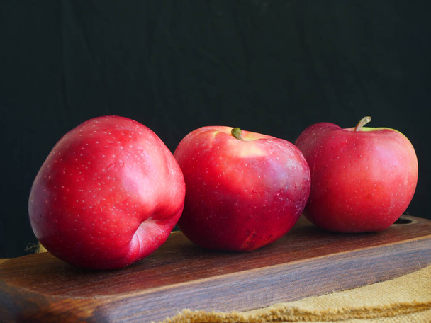 3つの赤いリンゴ、暗い背景、フルーツのクローズアップ - 写真・画像