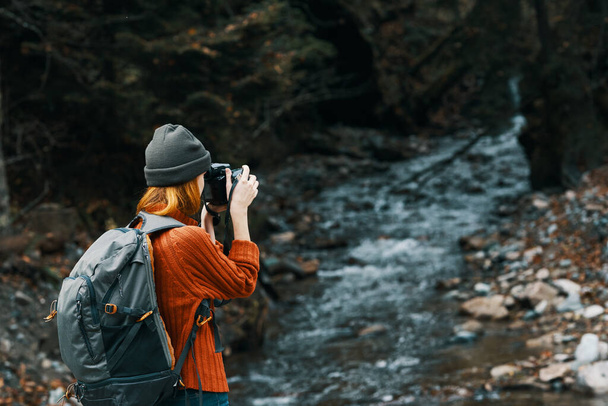 woman with a camera on nature in the mountains near the river and tall trees forest landscape - Photo, Image