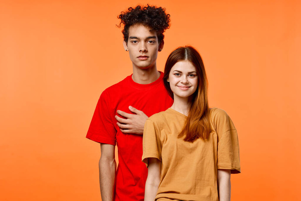 chico y chica en coloridas camisetas divertido estudio naranja fondo - Foto, imagen