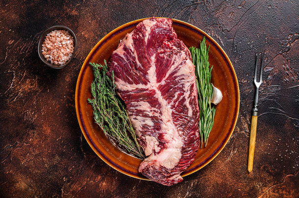 Bifteck de viande de bœuf tendre ou ongle cru suspendu sur une assiette rustique avec des herbes. Fond sombre. Vue du dessus - Photo, image