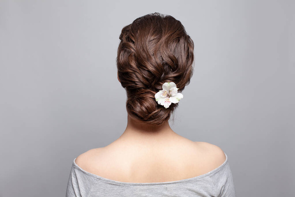 Schöne Frau Rücken und Kopf mit perfekter Frisur und weiße Blume auf weißem Hintergrund - Foto, Bild