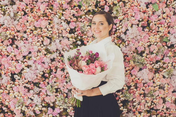 Heureuse femme mignonne avec bouquet de fleurs sur fond floral - Photo, image
