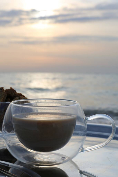 ranní káva na stříbrném podnosu ve slunečních paprscích svítání na pobřeží - Fotografie, Obrázek
