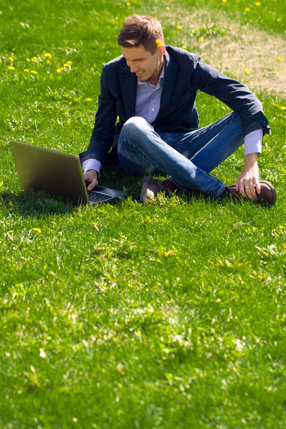 young business man on the grass. talking skype. outdoor.  - Valokuva, kuva