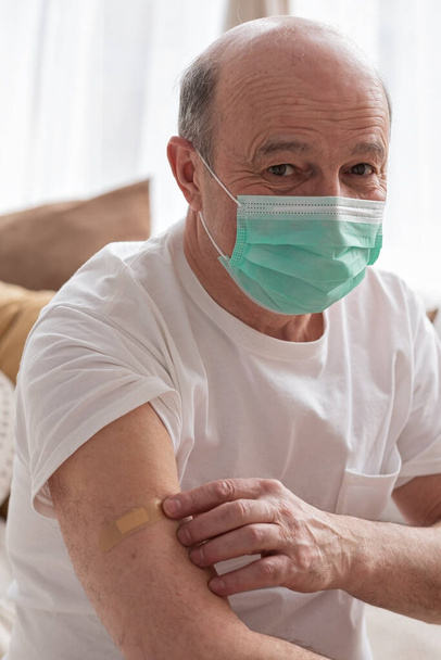 Senior hispanic man wearing face mask showing vaccinated arm. - Photo, Image