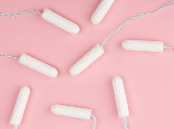 Medical female tampon on a pink background. Hygienic white tampon for women. Cotton swab. Menstruation, means of protection. Tampons on a red background. - Photo, Image
