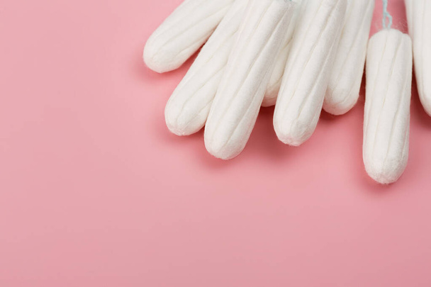 Medische vrouwelijke tampon op een roze achtergrond. Hygiënische witte tampon voor vrouwen. Katoen wattenstaafje. Menstruatie, beschermingsmiddelen. Tampons op een rode achtergrond. - Foto, afbeelding