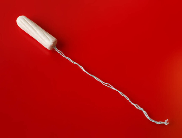 Lékařský tampón na růžovém pozadí. Hygienický bílý tampón pro ženy. Bavlněný tampon. Menstruace, ochranné prostředky. Tampóny na červeném pozadí. - Fotografie, Obrázek