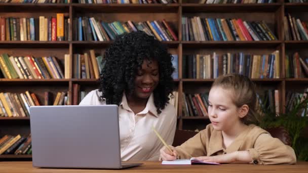 Musta opettaja ja koulutyttö antavat toisilleen viisi pöydässä - Materiaali, video