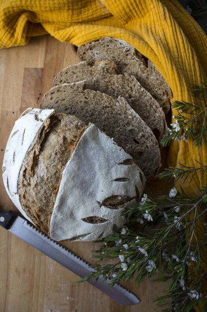 Pan crujiente en una toalla de cocina amarilla. Vista superior de la foto de pan de masa fermentada recién horneado. - Foto, imagen