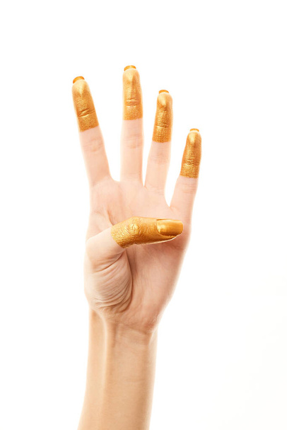 Hands in gold paint. Golden fingers. Female hand is showing numbers isolated on white background. Sign language. Hand numbers - Foto, Imagen