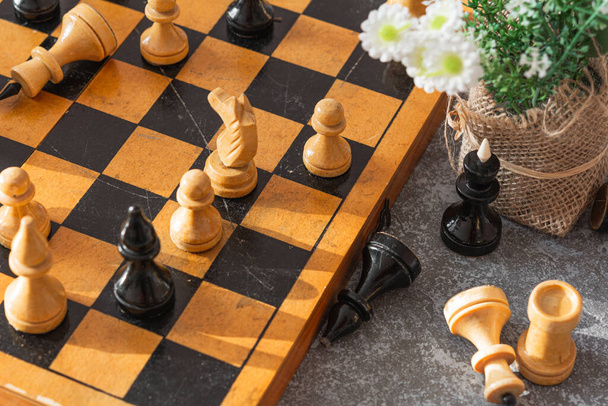 Schach. Schachbrett, Schachfiguren und Blumen auf graublauem Hintergrund an einem sonnigen Tag - Foto, Bild