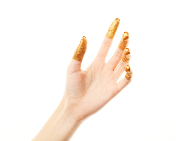 Handen in goudverf. Gouden vingers. Vrouwelijke hand geïsoleerd op witte achtergrond. De hand van een blanke vrouw met symbolen en gebaren. - Foto, afbeelding