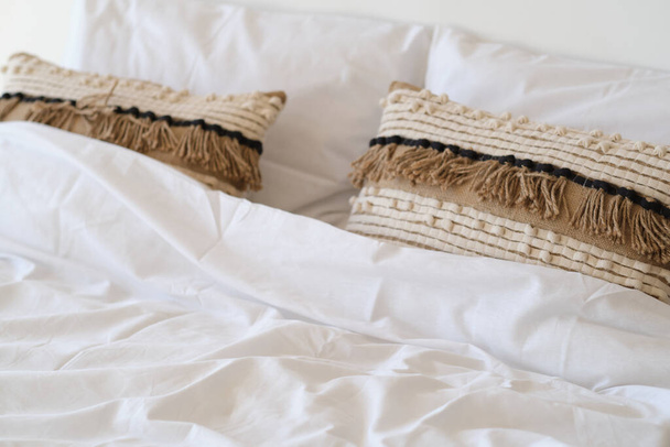 Schließen Sie weiße Bettwäsche und Kissen an der Wand Zimmer Hintergrund. Schlafzimmer mit bequemem Bett mit weichen weißen Kissen. - Foto, Bild