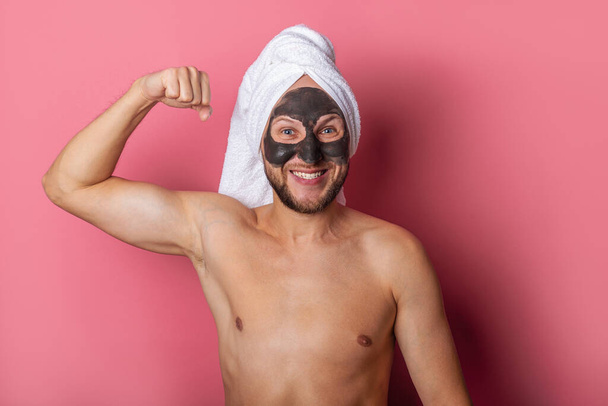 usmívající se muž s kosmetickou maskou na tváři, nahý ukazuje svaly na růžovém pozadí. - Fotografie, Obrázek