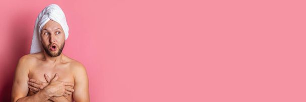 jovem com uma toalha na cabeça olha para o lado de surpresa em um fundo rosa. Banner - Foto, Imagem
