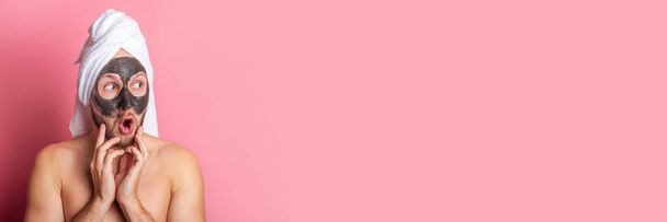 jovem surpreso com máscara cosmética em seu rosto em um fundo rosa. Banner. - Foto, Imagem