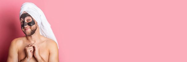 usmívající se mladý nahý muž s kosmetickou maskou na růžovém pozadí. Koncept péče o pleť. Nápis. - Fotografie, Obrázek