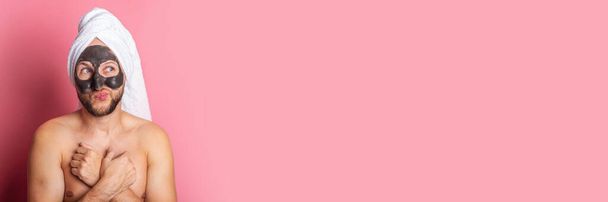 jovem aplica uma máscara facial hidratante, olha atentamente para o lado em um fundo rosa. Banner. - Foto, Imagem