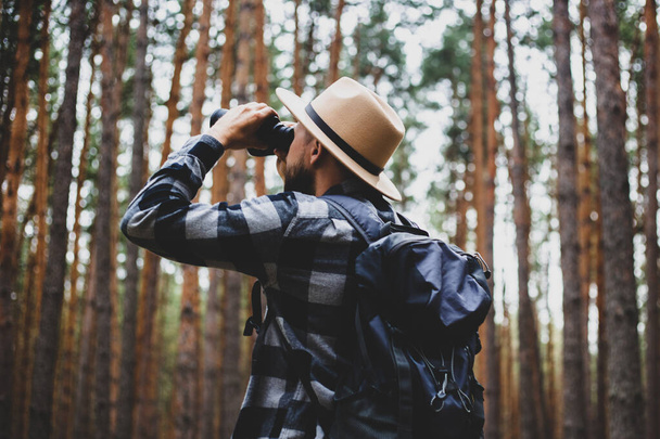 Männlicher Tourist blickt durch Fernglas in den Wald. - Foto, Bild