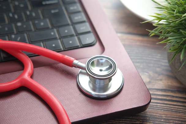 Medizinisches Stethoskop auf Laptop auf Holztisch  - Foto, Bild