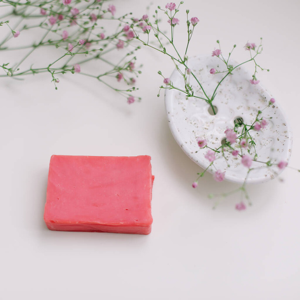 Natural handmade soap bar with ceramic soap dish and flowers, spa organic soap, sustainable lifestyle - Valokuva, kuva