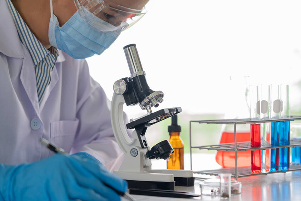 científicos que investigan en laboratorio en bata de laboratorio blanca, guantes que analizan, mirando la muestra de tubos de ensayo, concepto de biotecnología. - Foto, Imagen