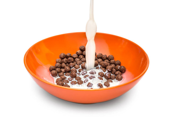 Молоко вливається в миску з шоколадними кульками на білому тлі
. - Фото, зображення