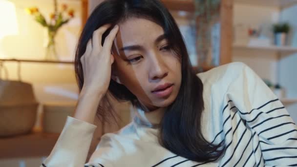 Nachdenkliche Asiatin mit Schlaflosigkeit sitzt nachts auf Sofa im Wohnzimmer und fühlt sich einsam, Trauriger depressiver Teenager bleibt allein zu Hause, Soziale Distanz, Coronavirus-Quarantäne. - Filmmaterial, Video