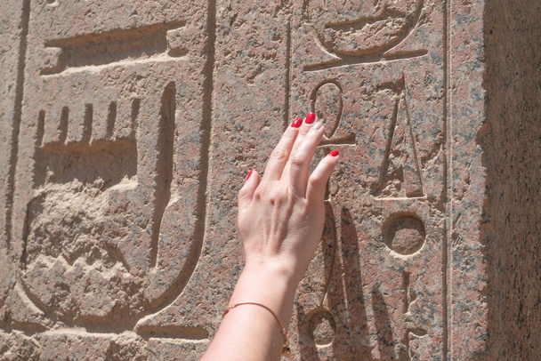 Рука женщины касается египетского иероглифа - Фото, изображение
