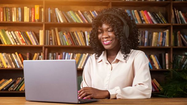 Afro-Amerikaanse vrouw heeft videocall uit home library - Foto, afbeelding