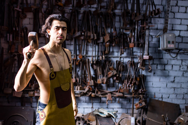 Hombre indio guapo auténtico en la industria del martillo del delantal de cuero pequeña empresa - Foto, Imagen