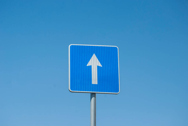 Синий прямоугольник в одну сторону дорожный знак крупным планом на голубом фоне неба - Фото, изображение