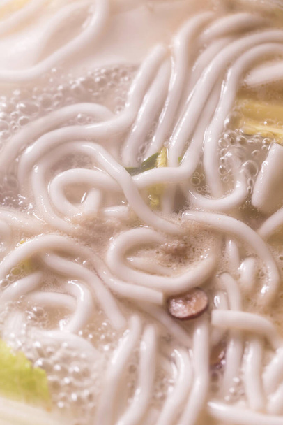 Προσθέστε διάφορα συστατικά στην σούπα που βράζει στην καυτή κατσαρόλα - Φωτογραφία, εικόνα
