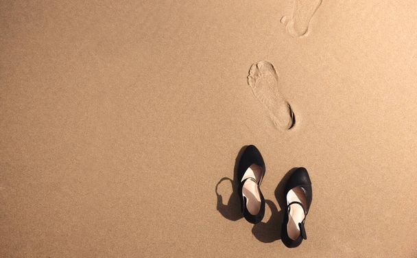 Work Life Balance Konzept. Geschäftsfrau zieht ihre Arbeitsschuhe aus und lässt sie an einem sonnigen Tag am Sandstrand für einen Spaziergang ins Meer zurück. Kündigen Sie Ihren Job, Büroausflug oder Sommerurlaub. Ansicht von oben - Foto, Bild