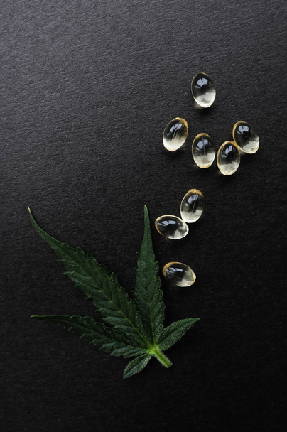 Foglie di cannabis medicinali con olio di CBD. Olio di marijuana in capsule mediche isolato su sfondo nero. - Foto, immagini