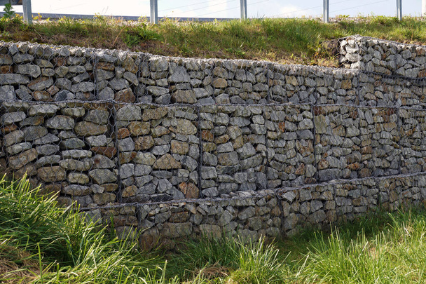 Un fragmento de un muro de contención hecho de gaviones. Fortalecimiento de la pendiente pronunciada. - Foto, imagen