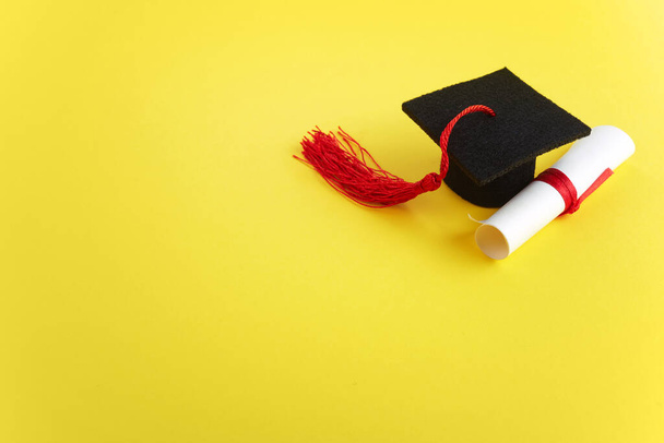 Academic hat with diploma on yellow background. Graduation theme - Photo, image