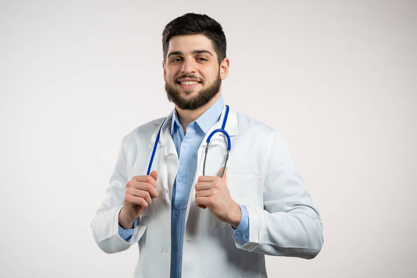 Portrait of cheerful doctor in professional medical coat. Man bearded doc isolated on white background. Medical staff concept. - Фото, изображение