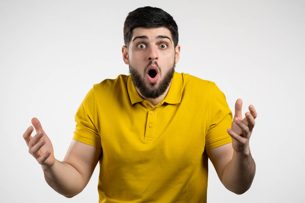Man depicts amazement, shows WOW delight face effect. Surprised excited happy guy in yellow wear. Handsome male shocked model on white background. - Фото, зображення