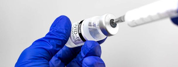 Orvosi kézben lévő injekciós tűvel és vakcinával ellátott orvosi fecskendő, injekciós fogalom banner fotó - Fotó, kép