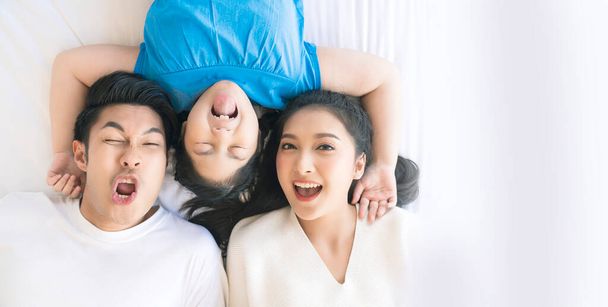 Happy Attractive Young asian Family Portrait Healthy harmony in life family day concept asian family man woman and little girl having good time together.top view bedroom mattress - Фото, изображение