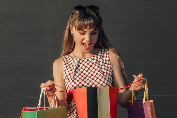 Close up portrait of young surprised woman with shopping bags standing outside, open her mouth. Black friday concept. - Photo, Image