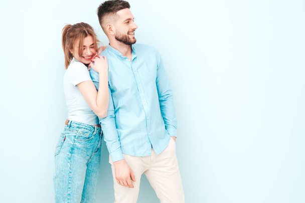 Smiling beautiful woman and her handsome boyfriend. Happy cheerful family having tender moments near light blue wall in studio.Pure cheerful models hugging.Embracing each other - 写真・画像